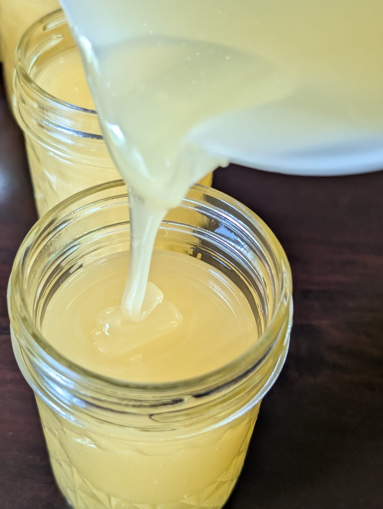 Creamed honey pouring into a glass jar